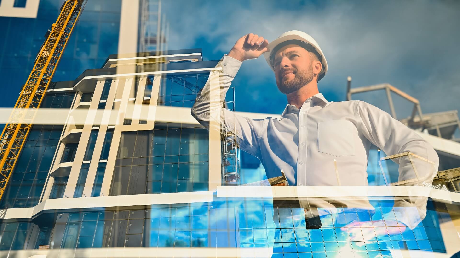 A double exposure image of a smiling construction engineer in a white hard hat overlaid with a modern glass commercial office building design.